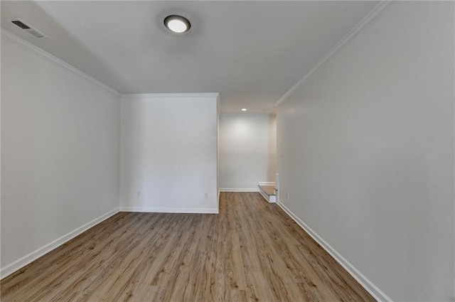 empty room with crown molding, baseboards, visible vents, and wood finished floors