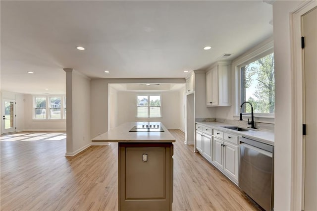 kitchen with a sink, a healthy amount of sunlight, a kitchen island, and dishwasher