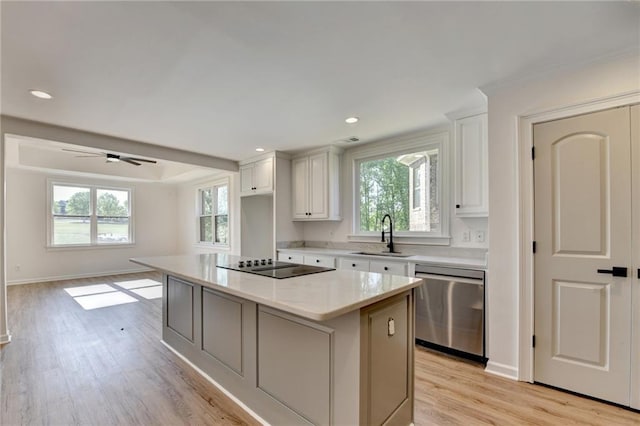 kitchen with light wood-type flooring, black electric cooktop, white cabinets, a sink, and dishwasher