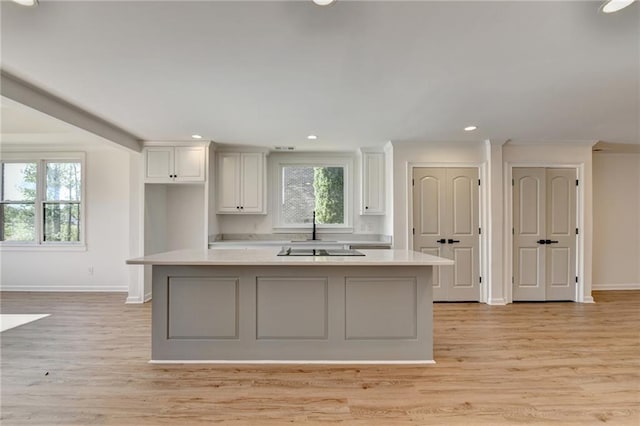 kitchen with baseboards, light countertops, white cabinetry, and light wood-style floors