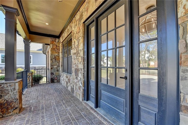 doorway to property featuring covered porch and stone siding