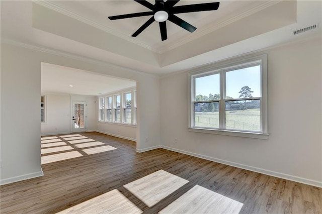 unfurnished room with visible vents, ornamental molding, wood finished floors, a tray ceiling, and a ceiling fan