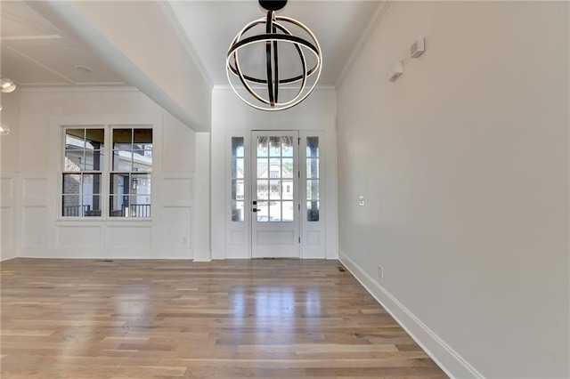 foyer with ornamental molding, wood finished floors, a notable chandelier, and a wealth of natural light