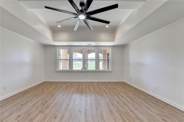 unfurnished room with crown molding, a tray ceiling, and light wood-style flooring