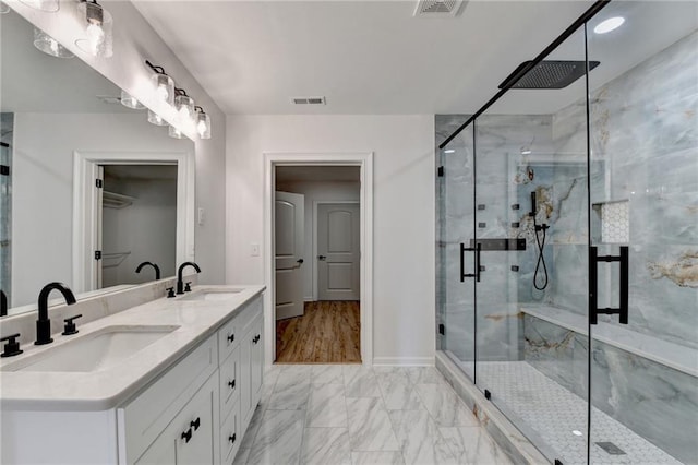 full bathroom with a sink, a marble finish shower, marble finish floor, and visible vents