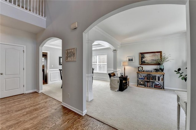 carpeted entryway with baseboards, arched walkways, and ornamental molding