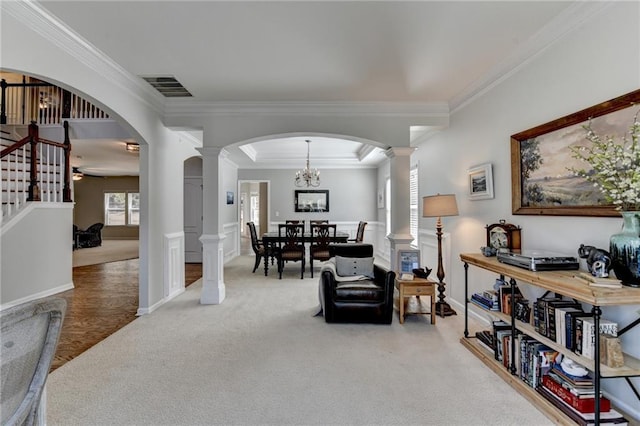 sitting room with visible vents, crown molding, light colored carpet, arched walkways, and ornate columns