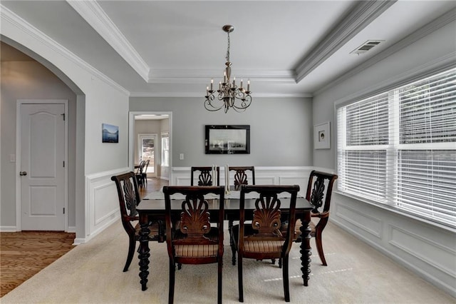 dining room featuring an inviting chandelier, a raised ceiling, visible vents, and arched walkways