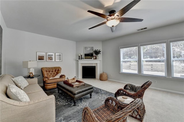 carpeted living area with visible vents, baseboards, a healthy amount of sunlight, and ceiling fan