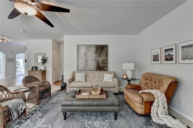 living room with a ceiling fan, arched walkways, and baseboards