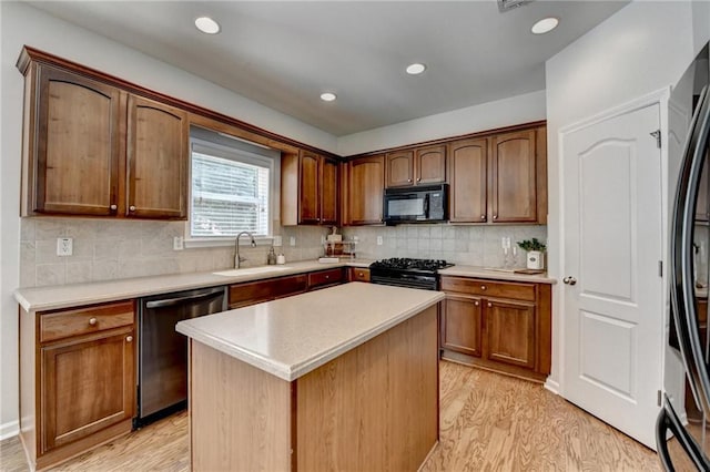 kitchen featuring a sink, tasteful backsplash, light wood-style floors, appliances with stainless steel finishes, and light countertops