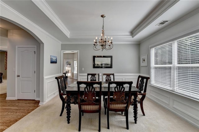 dining area featuring arched walkways, a notable chandelier, a raised ceiling, and a wealth of natural light