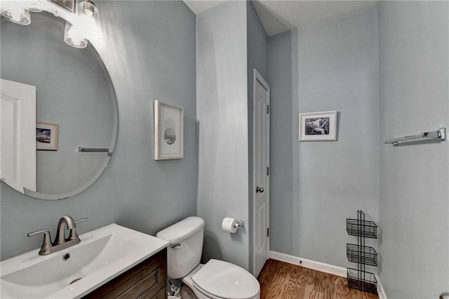 bathroom with baseboards, toilet, wood finished floors, and vanity