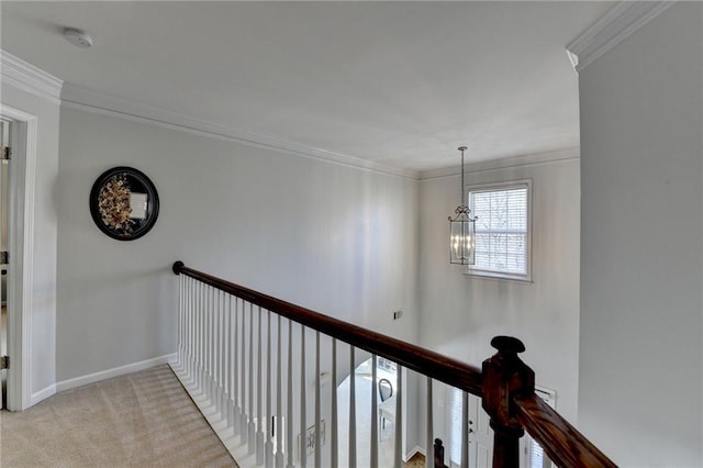 corridor featuring an upstairs landing, light carpet, a notable chandelier, ornamental molding, and baseboards