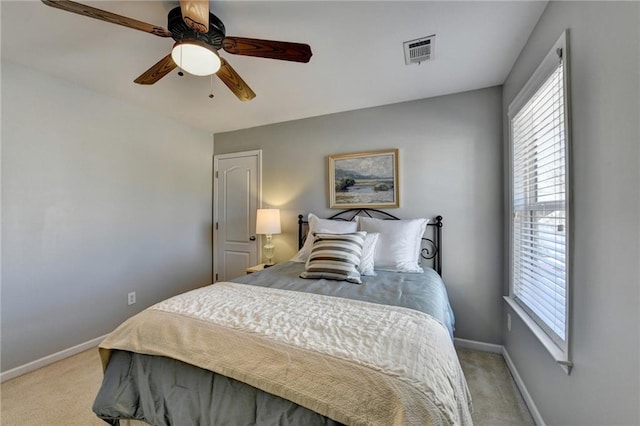 bedroom featuring a ceiling fan, baseboards, visible vents, and light carpet