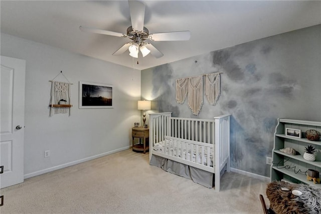 carpeted bedroom with a nursery area, baseboards, and ceiling fan