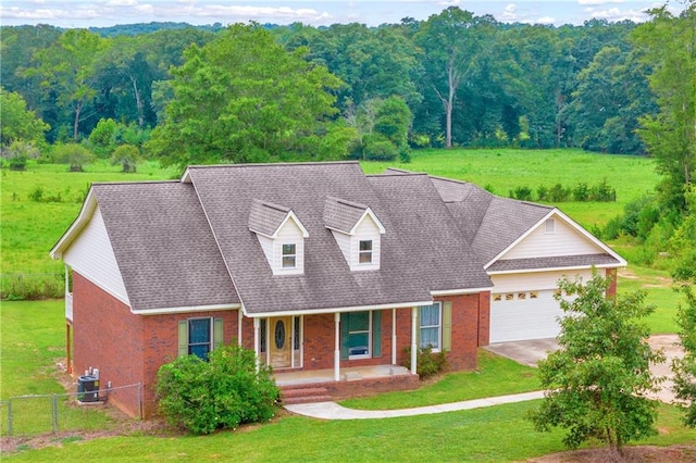 cape cod house with central air condition unit, a garage, covered porch, and a front lawn