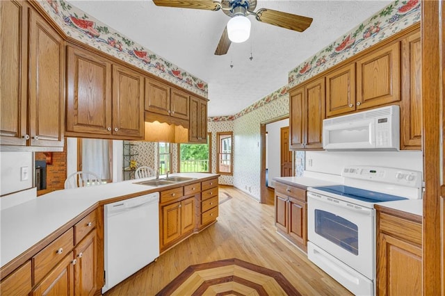 kitchen featuring white appliances, wallpapered walls, brown cabinetry, and light countertops