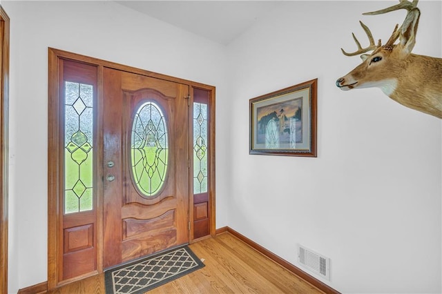 foyer featuring light wood-style flooring, baseboards, and visible vents