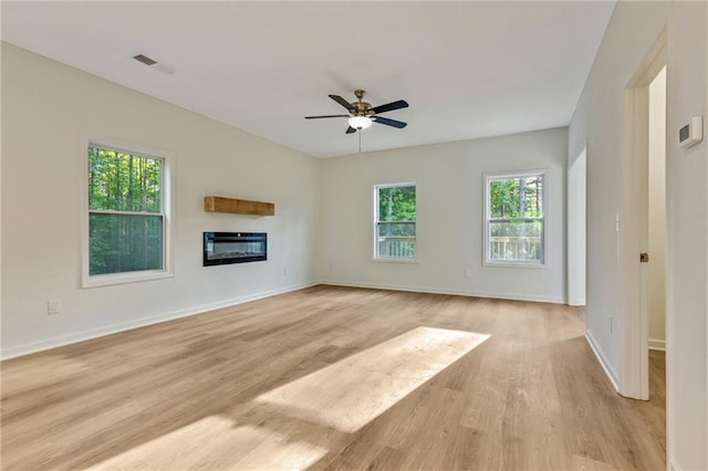 70 Wheeler Lake Path, Dallas, GA 30157 - unfurnished living room featuring healthy amount of natural light, light wood-style flooring, a glass covered fireplace, and a ceiling fan
