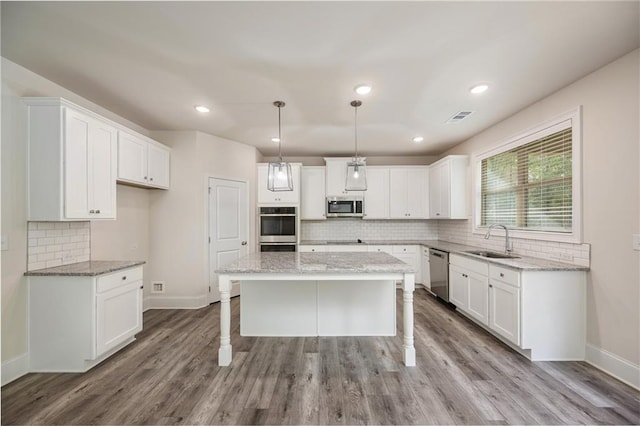 kitchen featuring stainless steel appliances, sink, light wood-type flooring, and a kitchen island