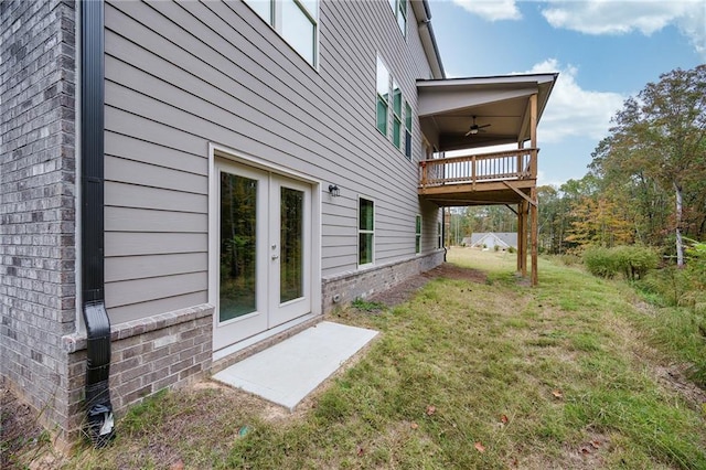 view of property exterior with french doors, a lawn, and ceiling fan