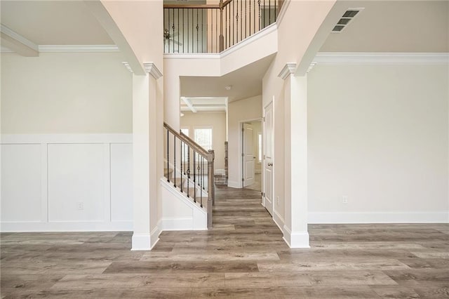 foyer entrance featuring ornamental molding, hardwood / wood-style flooring, and decorative columns