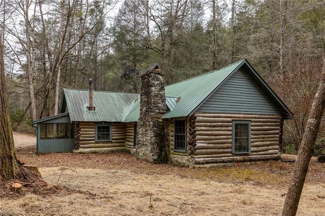 exterior space featuring log siding, a chimney, and metal roof