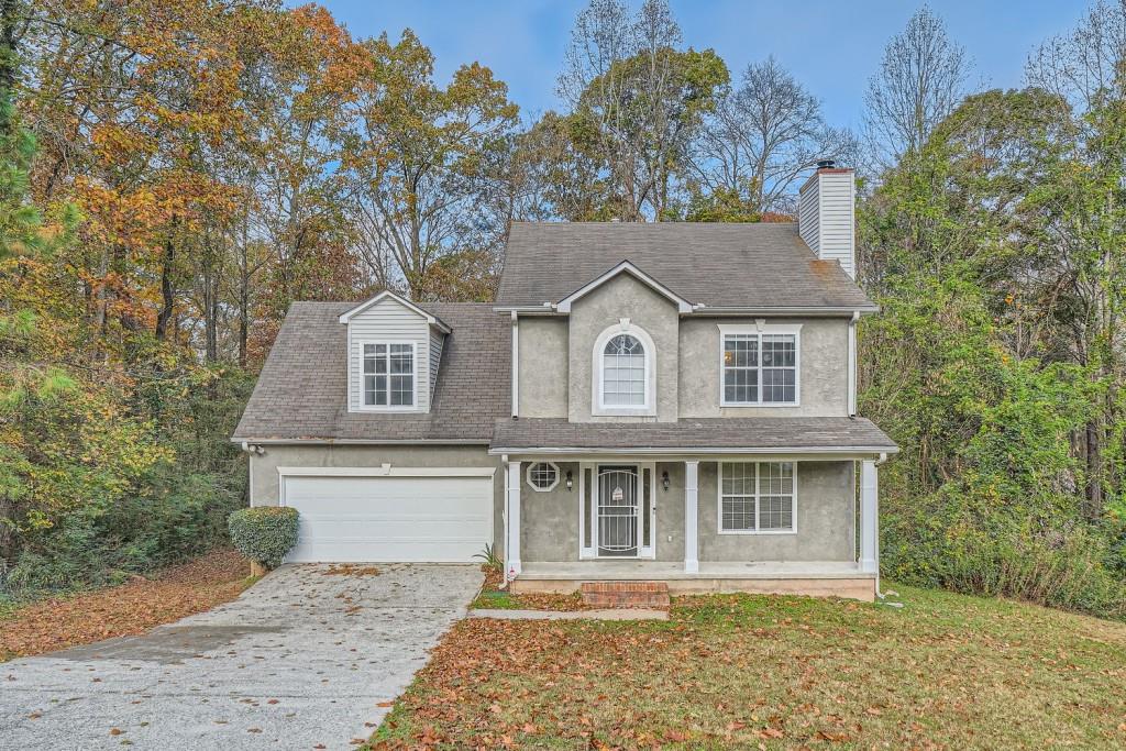 view of front of home featuring a front lawn, covered porch, and a garage