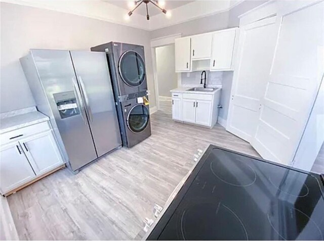 1127 Metropolitan Pkwy SW, Atlanta, GA 30310 - kitchen with stainless steel fridge, a sink, stacked washer / dryer, light wood-style flooring, and white cabinets