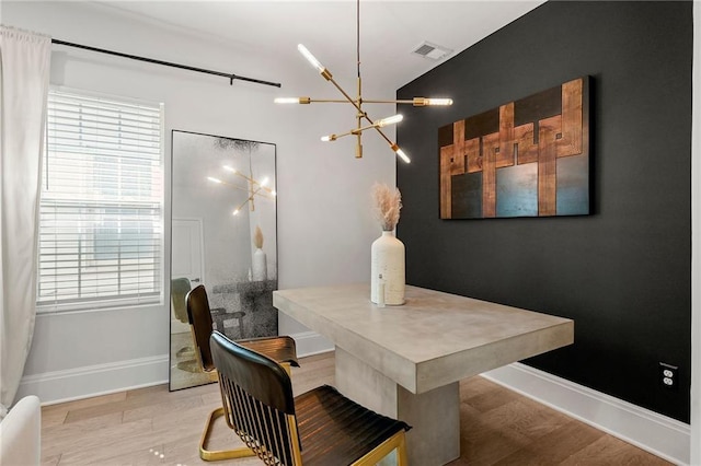 dining area featuring visible vents, baseboards, wood finished floors, and a chandelier