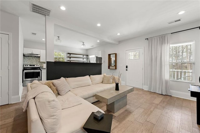 living room with a wealth of natural light, visible vents, recessed lighting, and light wood-style floors