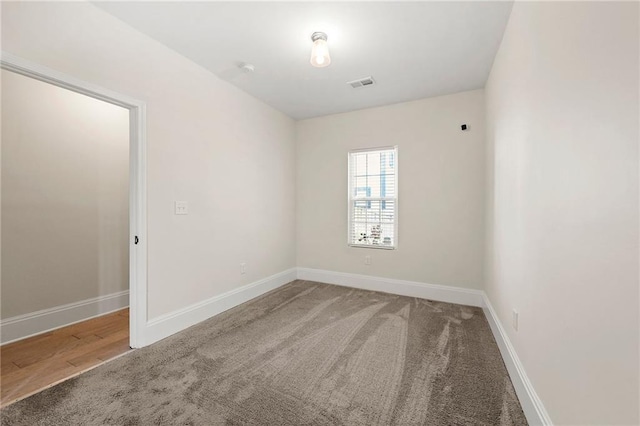 carpeted empty room featuring baseboards and visible vents