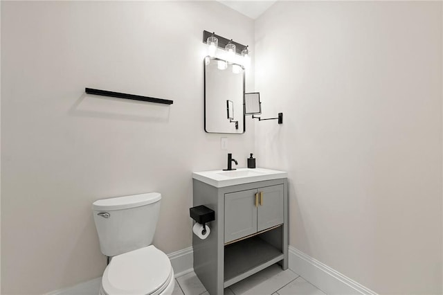 half bathroom featuring vanity, toilet, baseboards, and marble finish floor