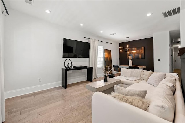 living room with visible vents, light wood finished floors, baseboards, recessed lighting, and a chandelier