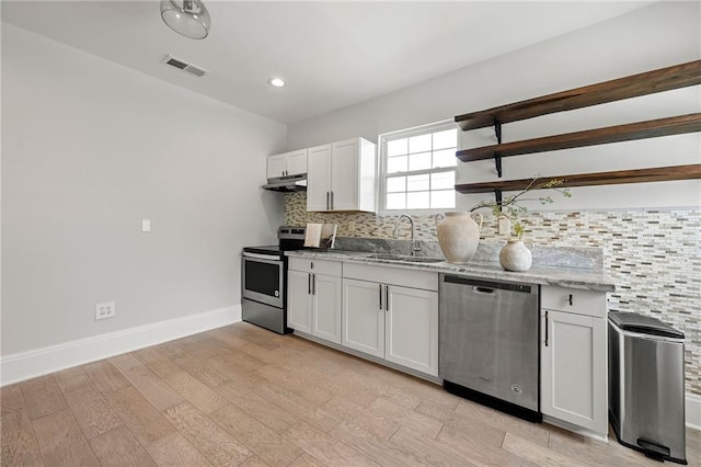 kitchen featuring visible vents, under cabinet range hood, decorative backsplash, appliances with stainless steel finishes, and a sink