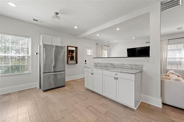 kitchen featuring light wood-style flooring, visible vents, white cabinets, and freestanding refrigerator