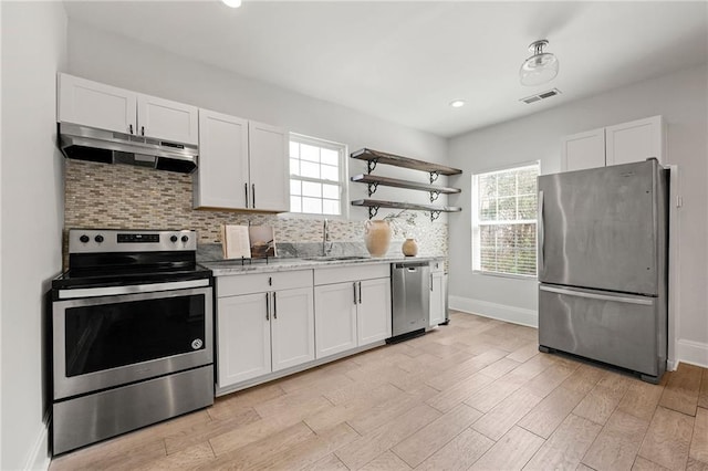 kitchen featuring open shelves, a sink, under cabinet range hood, appliances with stainless steel finishes, and tasteful backsplash