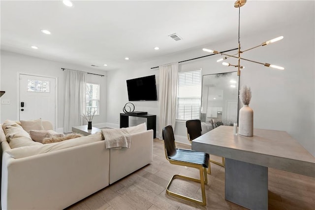 living room featuring visible vents, baseboards, recessed lighting, an inviting chandelier, and wood finished floors