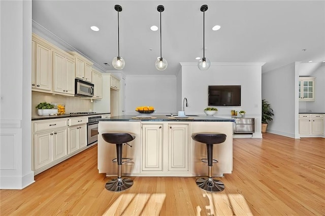 kitchen featuring appliances with stainless steel finishes, sink, a breakfast bar area, and cream cabinets