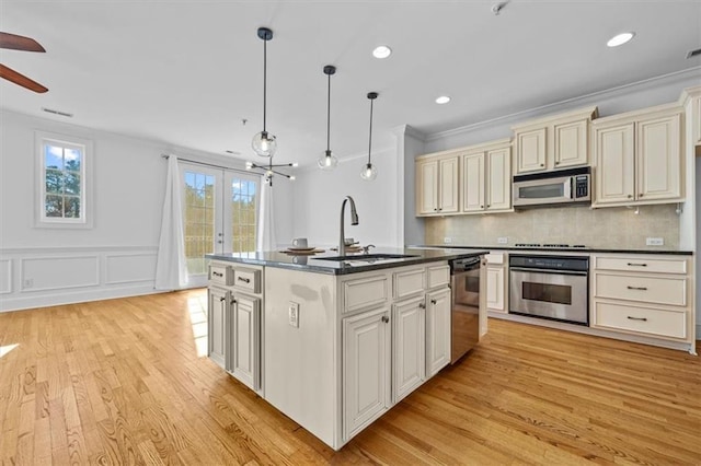 kitchen featuring backsplash, stainless steel appliances, sink, pendant lighting, and an island with sink