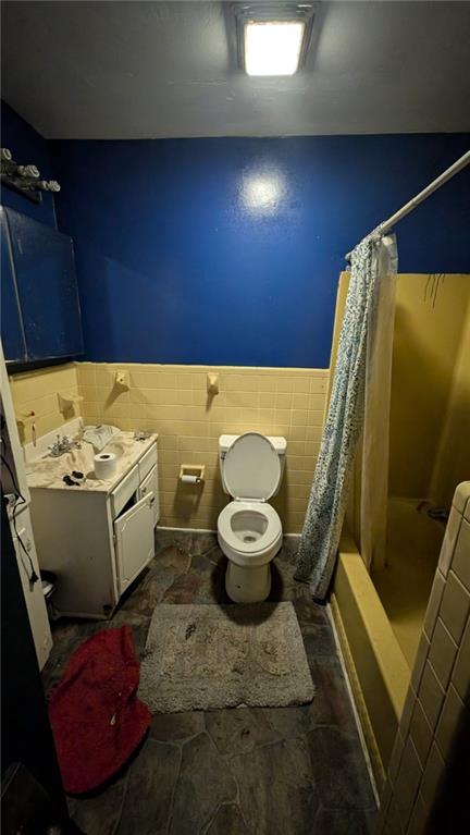 full bathroom featuring vanity, toilet, tile walls, and shower / tub combo