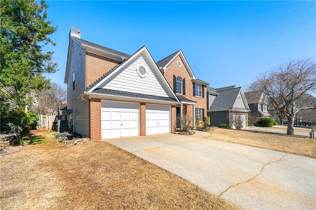 traditional-style home featuring driveway, an attached garage, a chimney, and brick siding