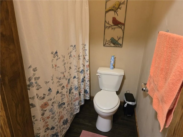 bathroom with curtained shower, wood finished floors, and toilet