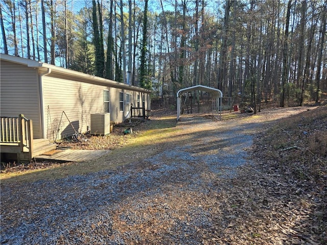 view of yard featuring a carport, gravel driveway, and central AC