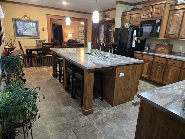 kitchen with a breakfast bar, brown cabinets, a sink, and black appliances