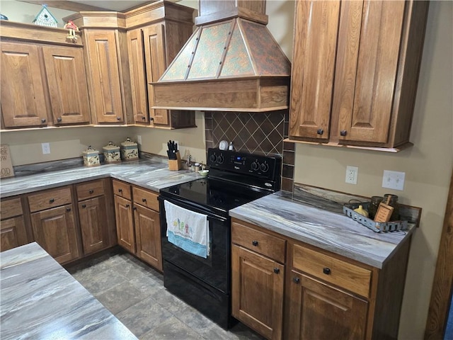 kitchen featuring light countertops, black range with electric stovetop, brown cabinetry, and custom range hood