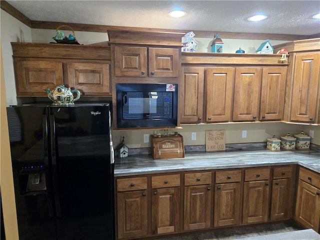 kitchen featuring a textured ceiling, recessed lighting, light countertops, brown cabinets, and black appliances