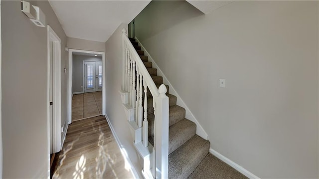 stairway with wood-type flooring and french doors