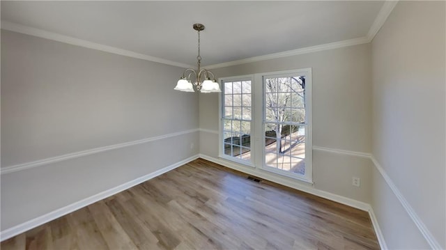 unfurnished dining area with crown molding, hardwood / wood-style flooring, and a chandelier